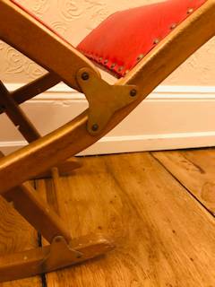 Repose-pieds à bascule ancien, structure bois, revêtement en similicuir rouge, pliable, réglable en hauteur, dimensions : L 65 cm, P 34 cm.