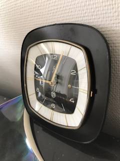 Horloge murale SMI, support formica carré, noir, aiguilles dorées, mécanisme quartz.