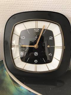 Horloge murale SMI, support formica carré, noir, aiguilles dorées, mécanisme quartz.